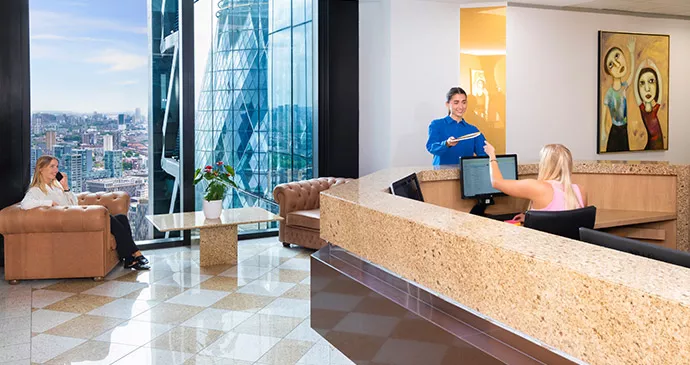 Servcorp receptionist handing mail to client. Client working in vibrant reception with a stunning view.